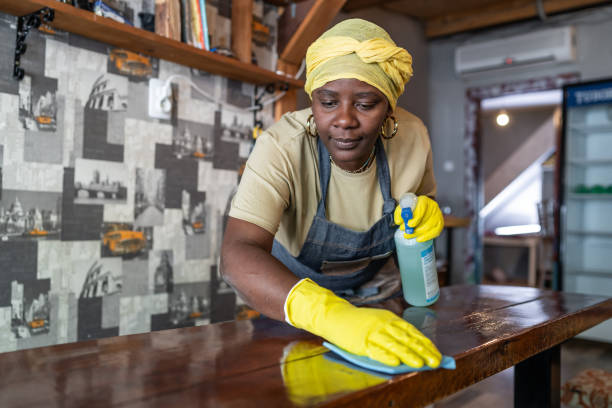 Afro female maid working at hostel disinfecting and preparing for the hostel guests after reopening